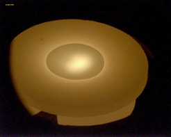 Fig. 2: Photograph of a Si source during evaporation at 800 °C (back side temperature). A melt pool on the front side is clearly visible. The diameter of the source is 12 mm.