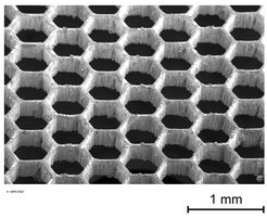 Scanning electron microscope image of a 200-μm-thick laser-cut tungsten foil with a honeycomb pattern used as gate electrodes in the thermoelectronic generators investigated.