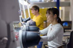 Laboratory environment with two researchers working on a glovebox system that provides closed gloves for the safe handling of materials.