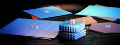 Mehrfarbige Nanostrukturen mit sechseckigem Muster, darunter ein gestapeltes Gebilde, auf einem dunklen Tisch präsentiert.